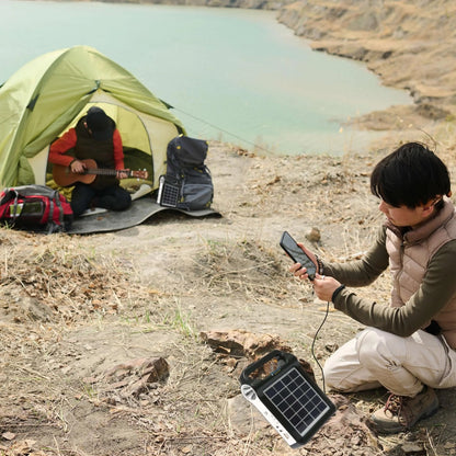 Portable solar power station charging a phone at a lakeside campsite