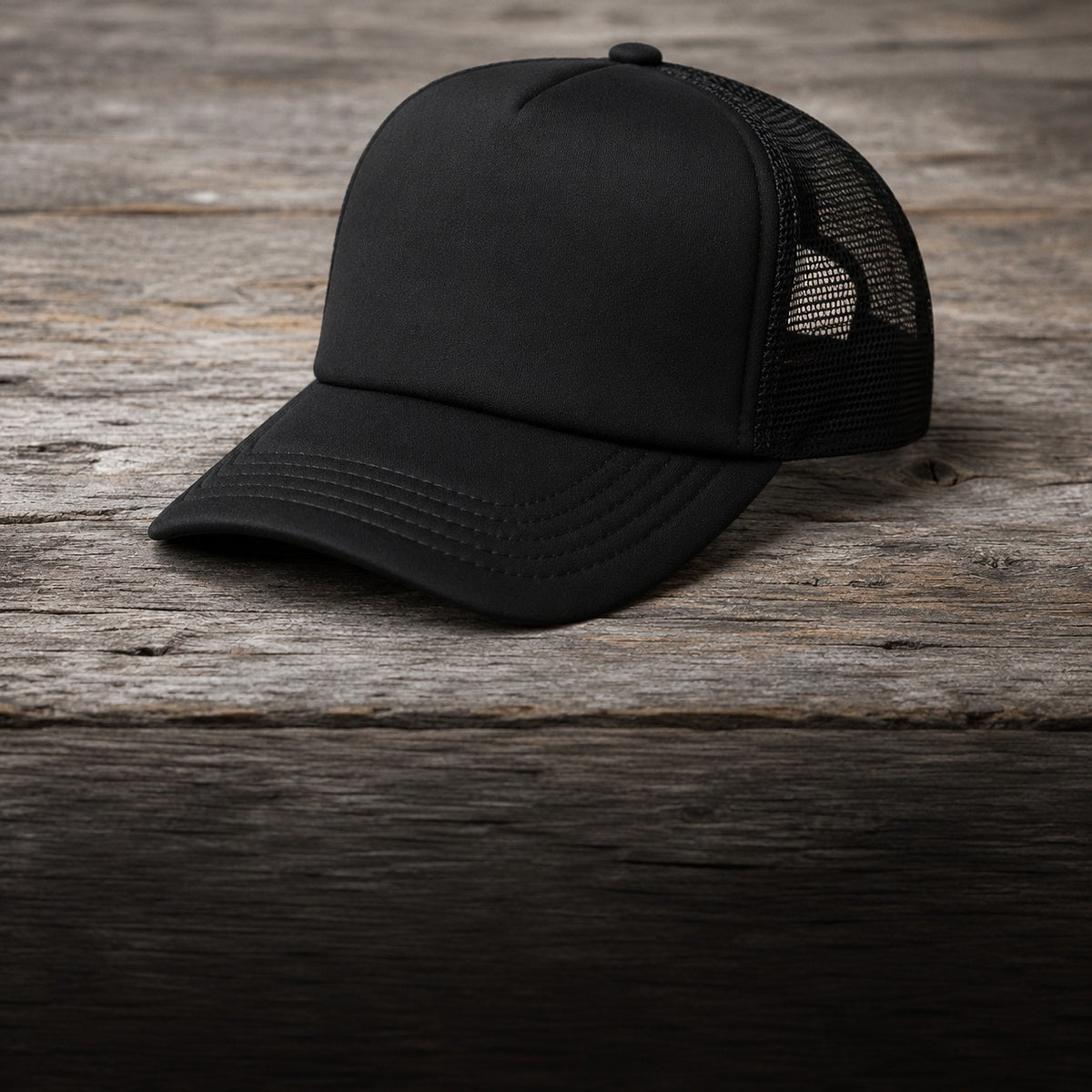 Black trucker cap on barnwood, three-quarter view showing the curved brim and mesh side panel
