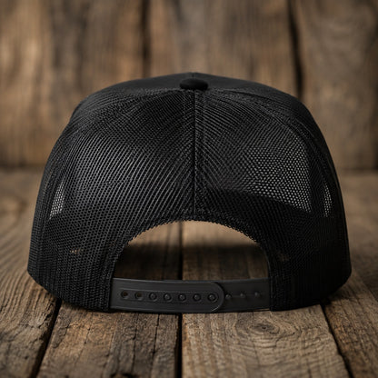 Rear view of the black trucker cap, adjustable buckle strap in focus