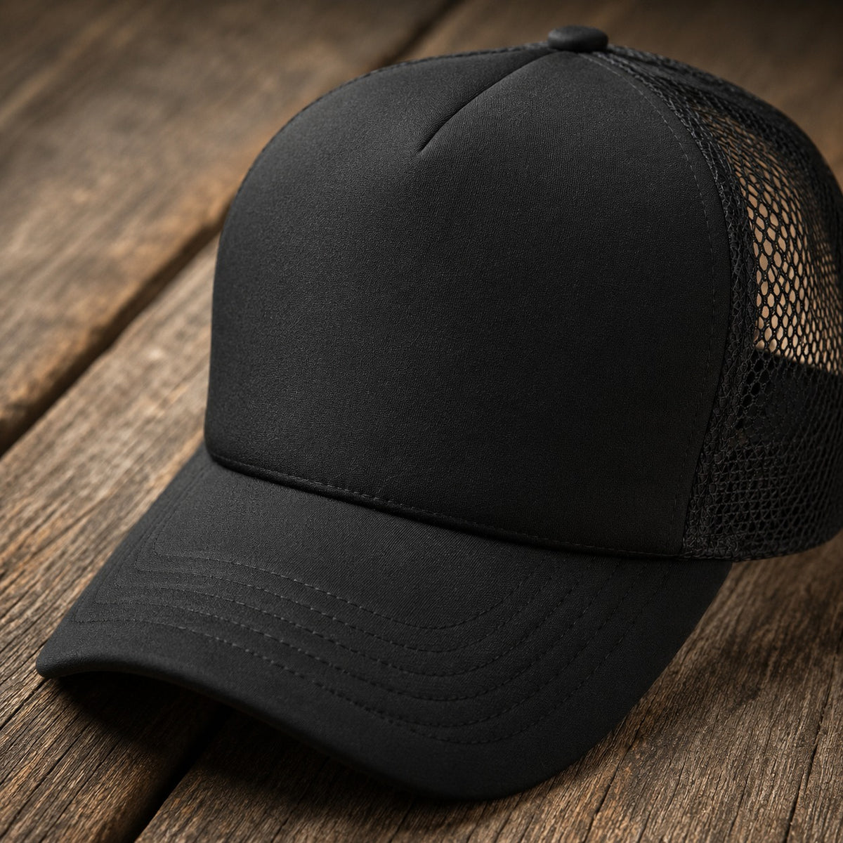 Side view of the black trucker cap showing the pre-curved top-stitched brim