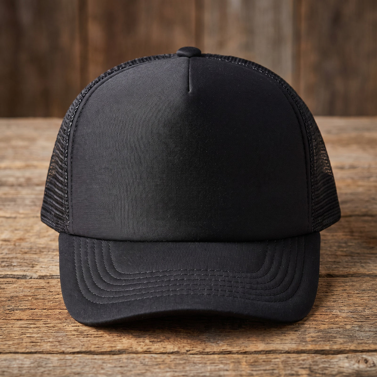 Front-on view of the black trucker cap showing the structured front panel and mesh sides