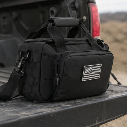 Gun and Utility Bag closed on a truck tailgate, front zip pocket and flag patch visible