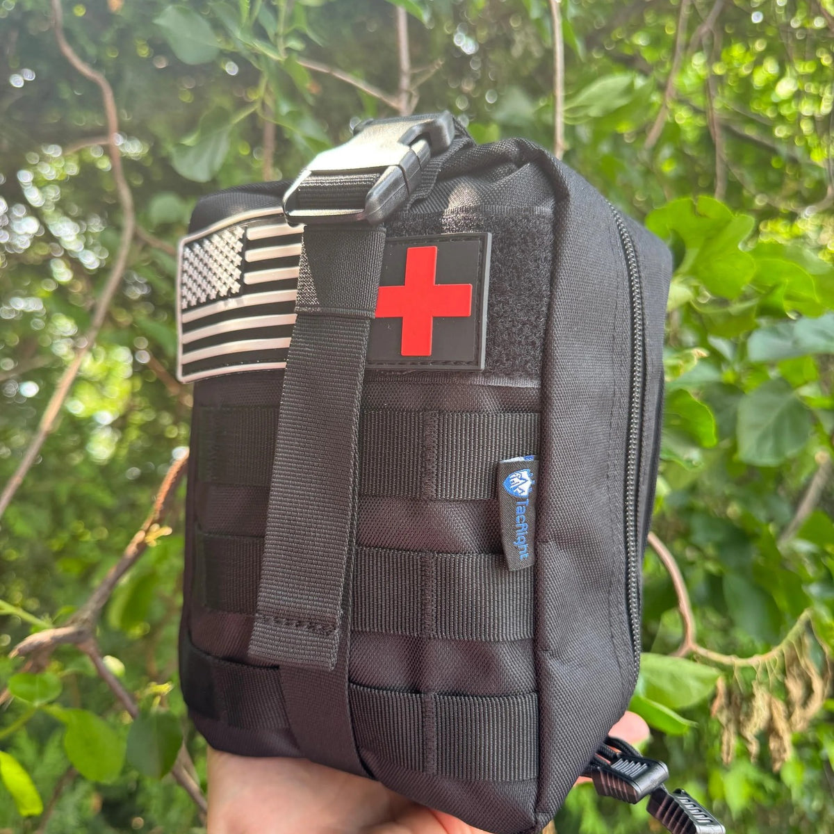 Trauma First Aid Kit held in one hand showing the MOLLE webbing and patches