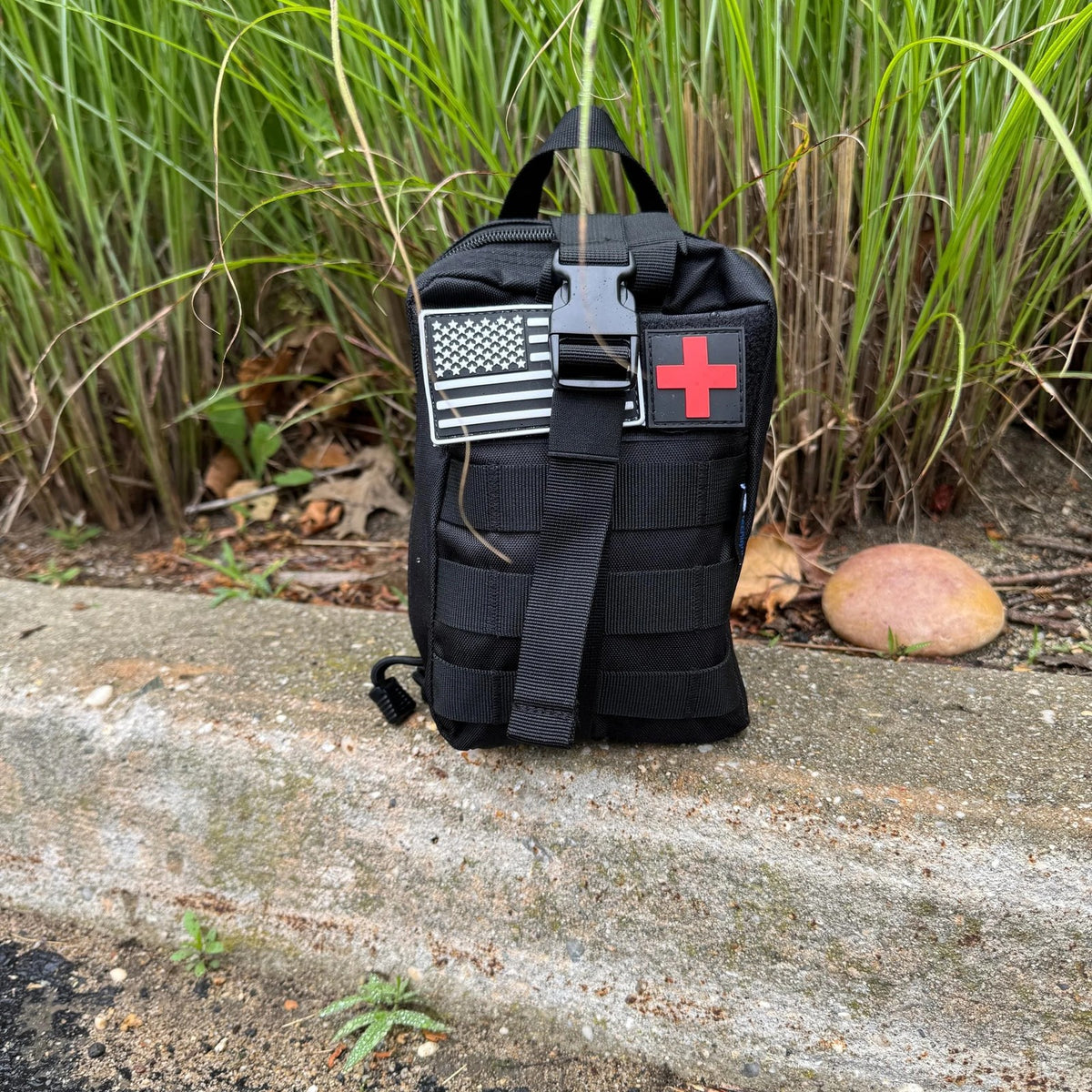 Trauma First Aid Kit outdoors on a concrete kerb beside long grass